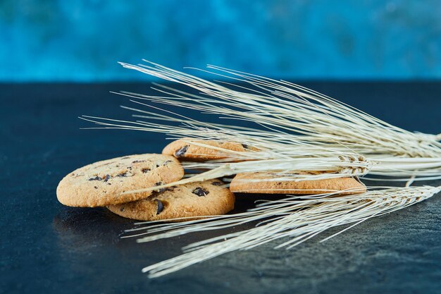 Biscotti al cioccolato su una superficie di marmo con spighe di grano