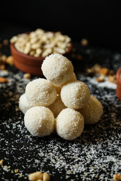 Biscotti al cocco vista frontale con fiocchi di cocco e noci su sfondo nero