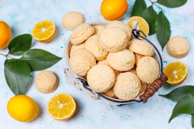 Biscotti al limone fatti in casa con limoni sulla superficie della luce