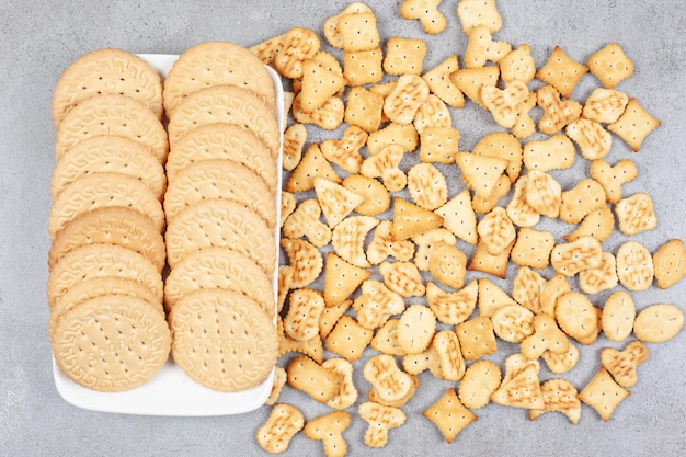 Biscotti allineati su un piatto accanto a patatine fritte sparse su fondo di marmo. Foto di alta qualità