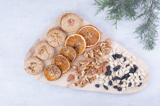 Biscotti, arance e noci varie su tavola di legno.