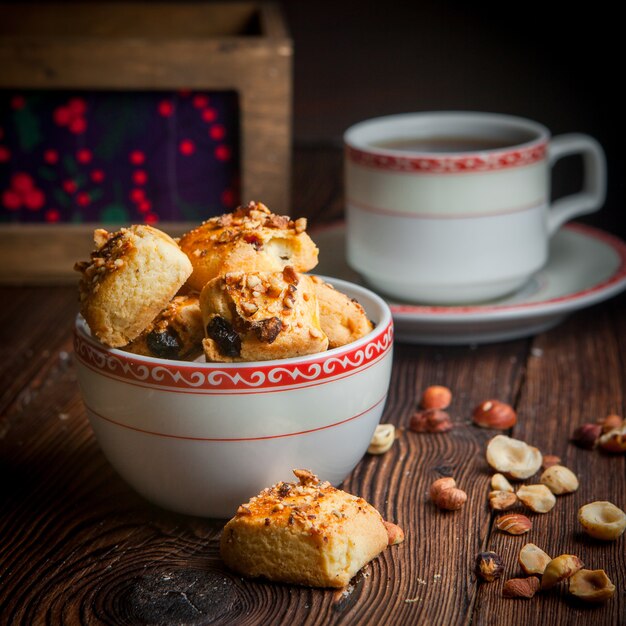 Biscotti casalinghi del primo piano di vista laterale con la tazza di tè sulla tavola di legno