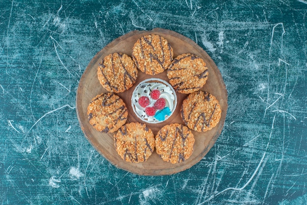Biscotti che circondano un cupcake su una tavola di legno su sfondo blu. Foto di alta qualità