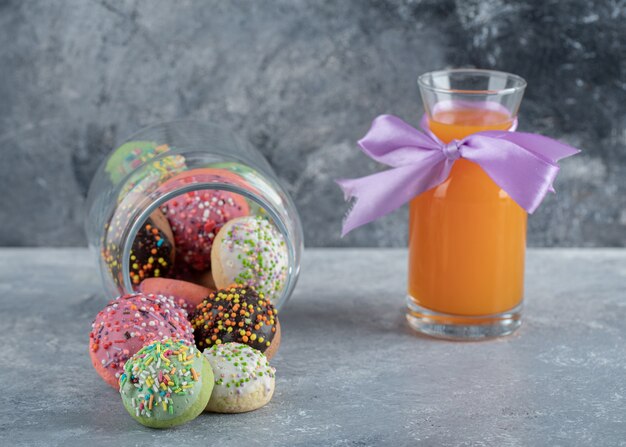 Biscotti colorati con granelli in barattolo di vetro e succo d'arancia.j