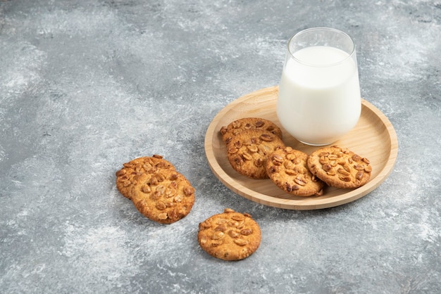 Biscotti con arachidi biologiche e bicchiere di latte sul piatto di legno.