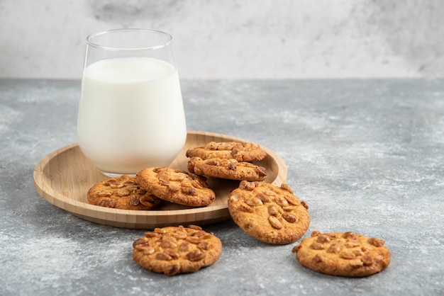 Biscotti con arachidi biologiche e bicchiere di latte sul piatto di legno.