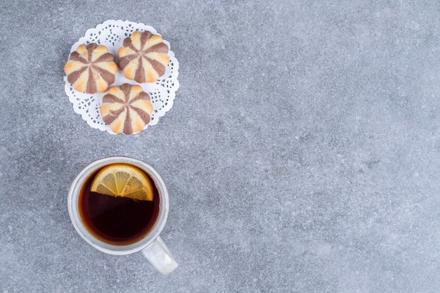 Biscotti con motivo a zebra e tazza di tè su superficie di marmo