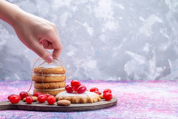 Biscotti cremosi del panino di vista più ravvicinata anteriore con cornioli rossi che prendono dalla femmina sul luminoso