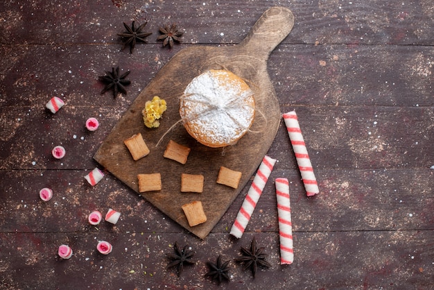 Biscotti del panino di vista superiore con crema insieme alle caramelle del bastone sulla caramella di zucchero dolce del biscotto del fondo marrone