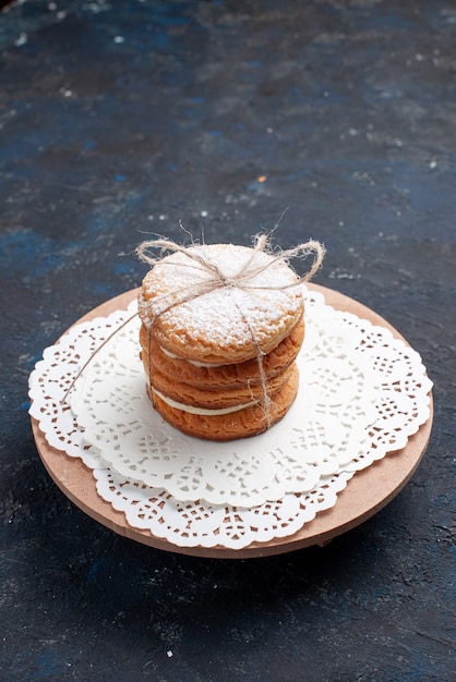 Biscotti deliziosi del panino di vista frontale legati squisiti sulla torta blu scuro della scrivania