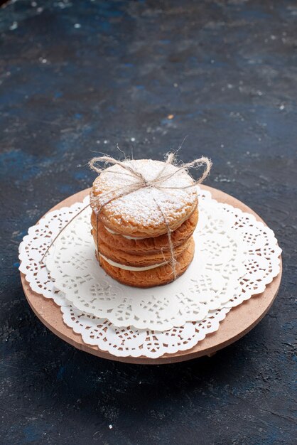 Biscotti deliziosi del panino di vista frontale legati squisiti sulla torta blu scuro della scrivania