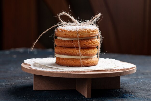 Biscotti deliziosi del panino di vista ravvicinata anteriore legati squisiti sulla torta blu scuro della scrivania