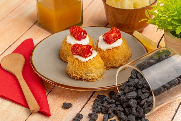 biscotti della pasticceria orientale all'interno del piatto con ananas essiccato crema bianca e frutta secca sulla tavola di legno