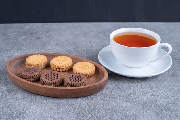 Biscotti di avena e cacao con tazza di tè su superficie di marmo