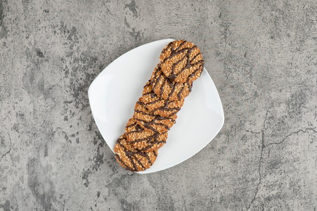 Biscotti di farina d'avena al forno freschi cosparsi di semi sul piatto bianco.