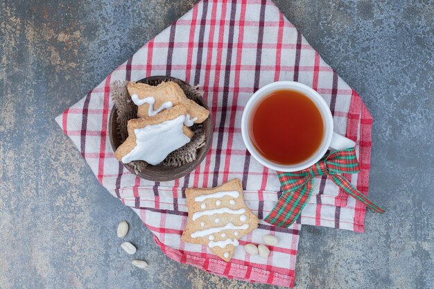 Biscotti di pan di zenzero a forma di stella e tazza di tè sulla tovaglia. Foto di alta qualità