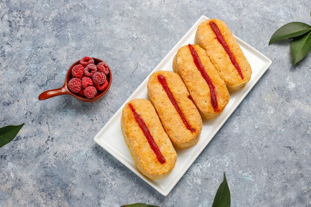 Biscotti di pasta sfoglia con marmellata di lamponi e lamponi congelati su luce