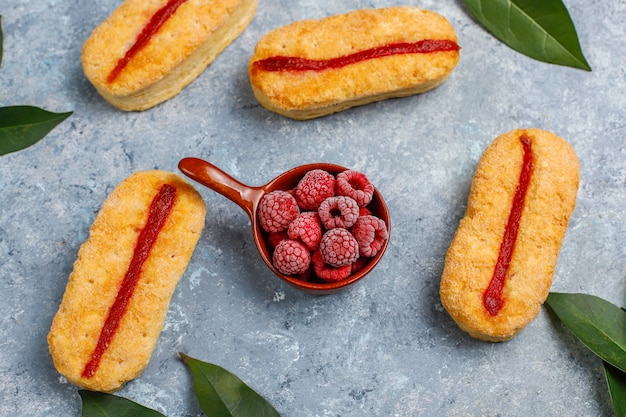 Biscotti di pasta sfoglia con marmellata di lamponi e lamponi congelati su luce