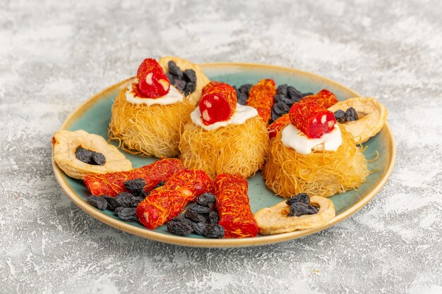 biscotti di pasticceria orientale all'interno di un piatto verde con frutta secca crema bianca e piccole confetture