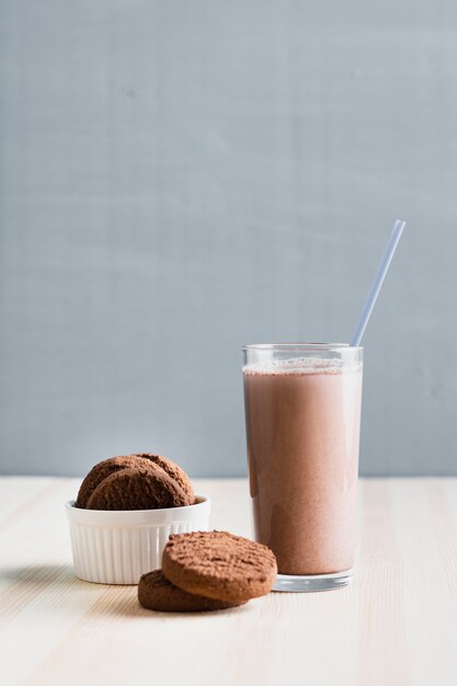 Biscotti di vista frontale con latte al cioccolato in vetro con paglia