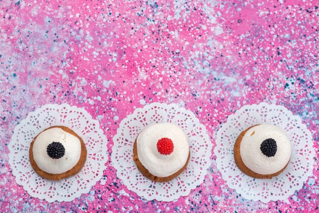 Biscotti di vista superiore con crema sul colore dolce dello zucchero del biscotto dello scrittorio colorato