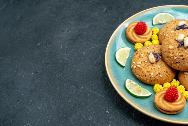 Biscotti di zucchero di vista frontale con le fette del limone su una torta dolce del biscotto del biscotto della torta del fondo grigio