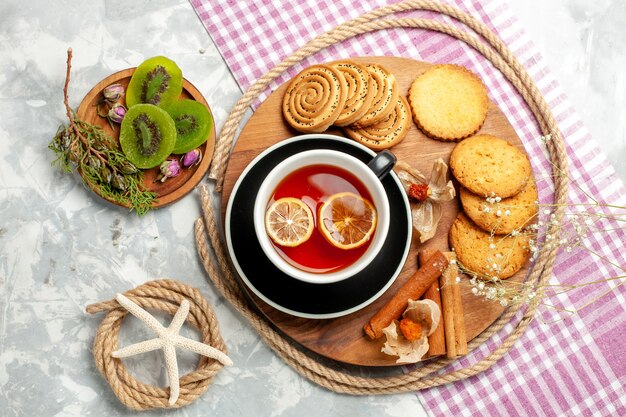 Biscotti di zucchero di vista superiore con la tazza di tè sulla torta dolce della torta del biscotto del biscotto della parete bianca