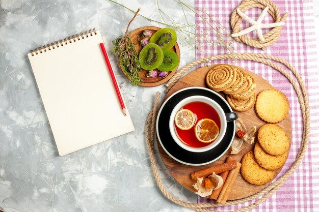 Biscotti di zucchero di vista superiore con la tazza di tè sulla torta dolce della torta del biscotto del biscotto della parete bianca