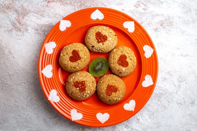 Biscotti di zucchero rotondi di vista superiore all'interno del piatto su una torta dolce dello zucchero del biscotto del biscotto di superficie bianca