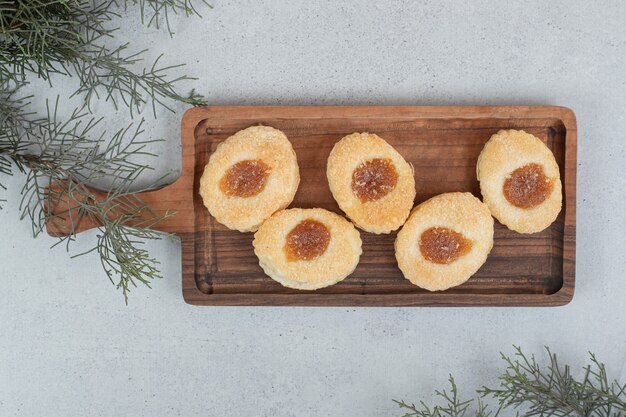 Biscotti dolci con marmellata su tagliere in legno