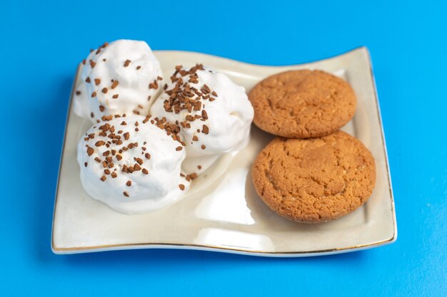 Biscotti dolci di vista frontale con delizioso gelato all'interno del piatto sulla scrivania blu