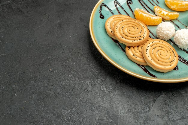 Biscotti dolci di vista frontale con le caramelle della noce di cocco all'interno della zolla sulla torta della caramella dei biscotti dello scrittorio grigio