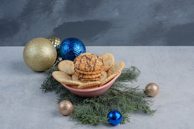 Biscotti e biscotti in una ciotola tra decorazioni natalizie sulla superficie in marmo