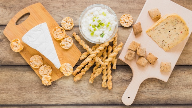 Biscotti e grissini del formaggio con formaggio in ciotola sul contesto di legno