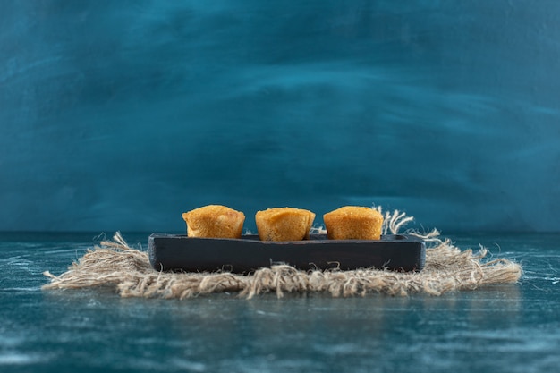 Biscotti fatti in casa su un piatto di legno su un asciugamano, sullo sfondo blu. Foto di alta qualità