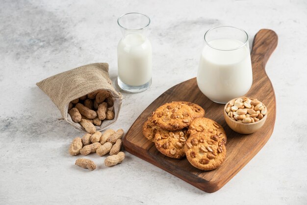 Biscotti gustosi con miele, latte e arachidi su tavola di legno.