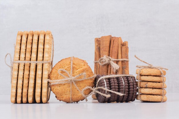 Biscotti in corda con bastoncini di cannella sul tavolo bianco.