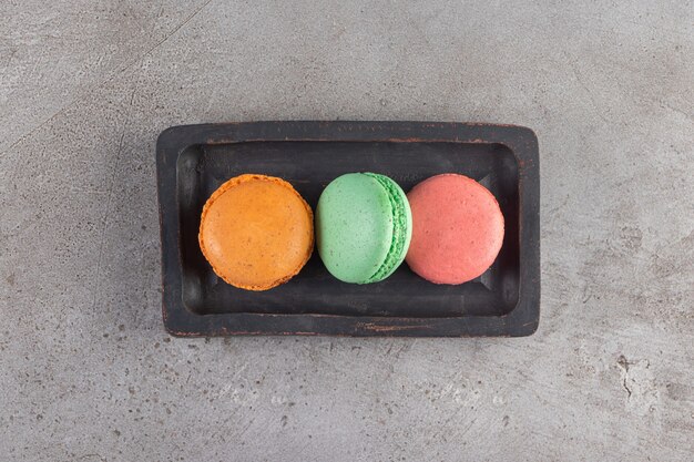 Biscotti maccheroni di diversi colori in una tavola di legno scuro.