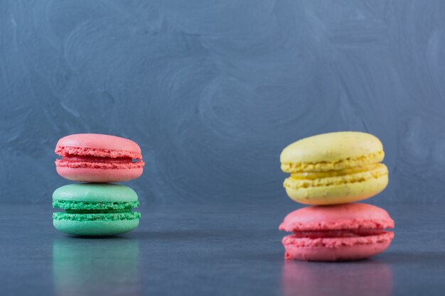 Biscotti maccheroni di diversi colori su una superficie grigio scuro