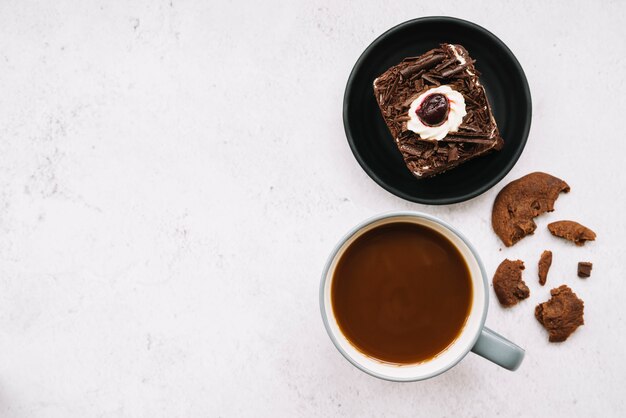 Biscotti mangiati; fetta di torta e tazza di caffè su sfondo bianco