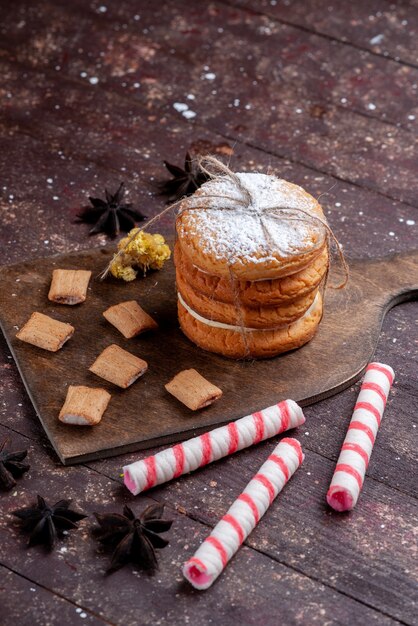 biscotti sandwich con panna insieme a caramelle stick sulla scrivania marrone