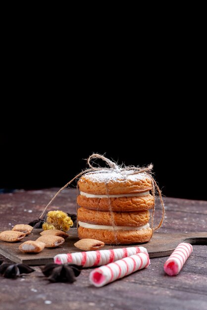 biscotti sandwich con panna insieme a caramelle stick sulla scrivania marrone