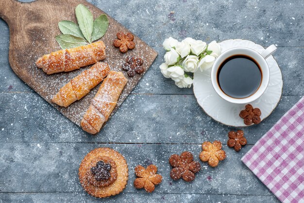 Biscotti squisiti dolci di vista superiore con la tazza di caffè e braccialetti dolci il caffè dolce dello zucchero del biscotto del fondo grigio