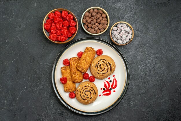 Biscotti squisiti dolci di vista superiore con le caramelle sulla torta dolce della caramella del biscotto dello zucchero del fondo grigio