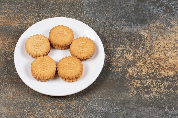 Biscotti squisiti riempiti di crema sulla zolla bianca.