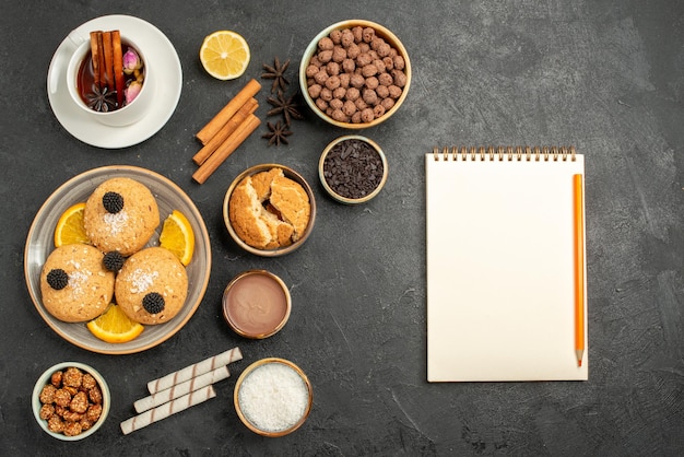 Biscotti squisiti vista dall'alto con una tazza di tè sulla superficie grigio scuro torta torta dessert biscotto tè biscotto