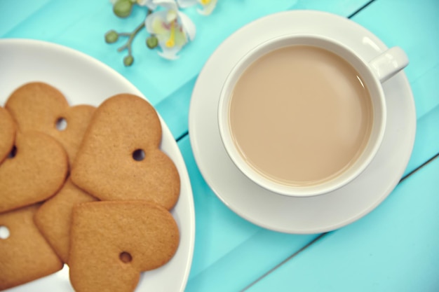 Biscotto di pan di zenzero a forma di cuore su piastra grigia con vista dall'alto della tazza di caffè Vecchio tavolo in legno