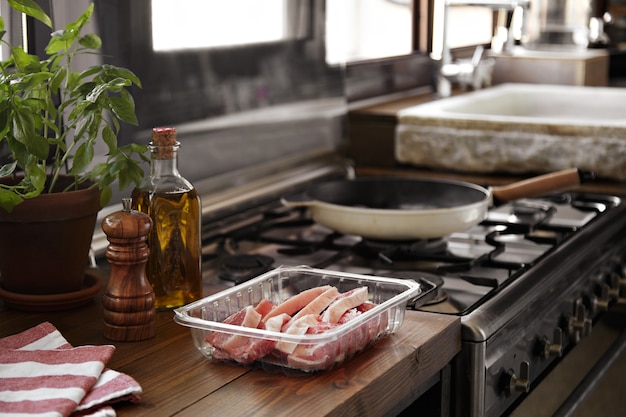 Bistecca a fette che sta per essere grigliata in una padella accanto a una finestra della cucina