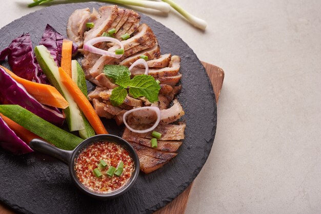 Bistecca alla griglia con verdure miste e spezie. Cibo gustoso fatto in casa. superficie di pietra. Bistecca di maiale con insalata. Il maiale alla griglia è uno dei piatti thailandesi più popolari. Maiale alla griglia con salsa piccante.