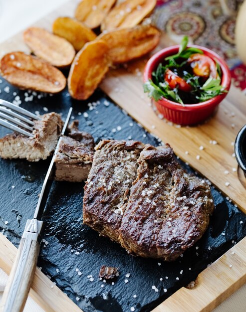 Bistecca con insalata di verdure e patate fritte.